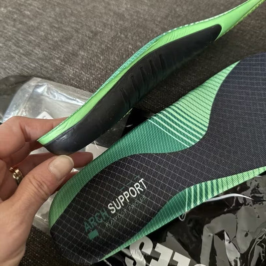 Green and black shoe insole with 'Arch Support' text held by a hand on a gray surface.