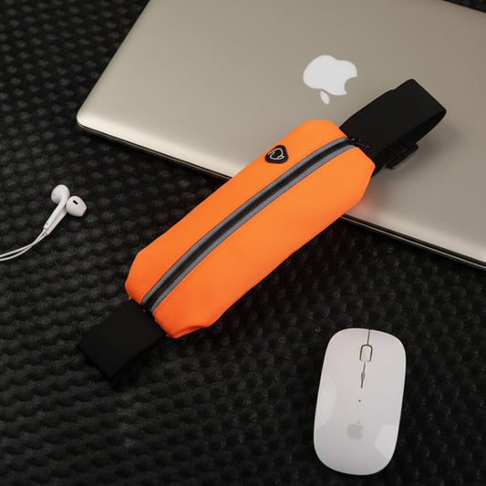 Orange waist bag on a black textured surface with a laptop, mouse, and earbuds.