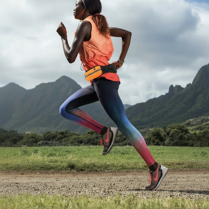 Person running with an orange waist bag on a mountain trail
