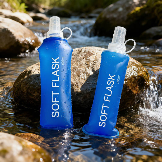 Two blue soft flasks labeled 'SOFT FLASK' in a natural setting with water and rocks.